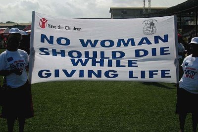 Women carrying a banner promoting support for safer birthing.