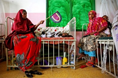 Mothers sit with their children in a hospital ward.
