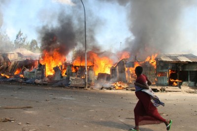 A pregnant woman runs past burning shacks in Nairobi during the 2007 post-election violence which led to the trials.