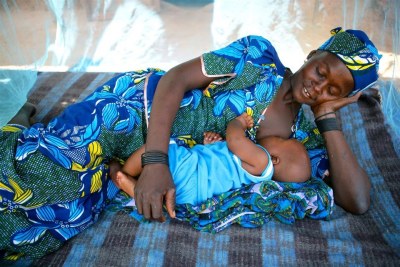 A woman breastfeeds her baby under a mosquito net in Garin Badjini village, Niger