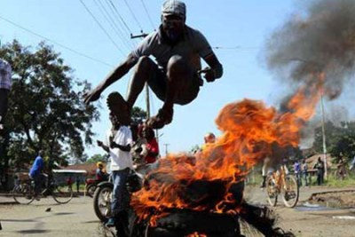 A protester jumps over burning tyres in Kisumu in western Kenya during anti-poll agency protests.