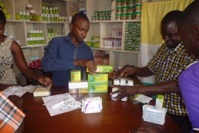 Wasswa (right) piles TIENS products up on the counter of the store in Iganga.