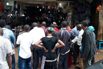 People gathered at one of the shops along Market Street in Kampala to watch television news about Assistant Inspector General of Police Andrew Felix Kaweesi's murder.