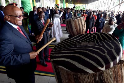 President Zuma beating the traditional drums as President Magafuli looks on.