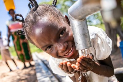 Une fillette au Zimbabwe boit de l'eau propre et salubre à un puits réhabilité avec le soutien de l'ONU.