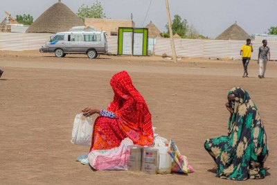 Internally displaced people (IDPs) wait for transport after food distribution at Un Gargor, Kassala where CARE has distributed Sorghum, lentils, salt, and cooking oil to over 6,000 people